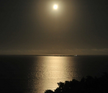 月あかりに照らされた夜の海。久高島が神々しく浮かぶ。